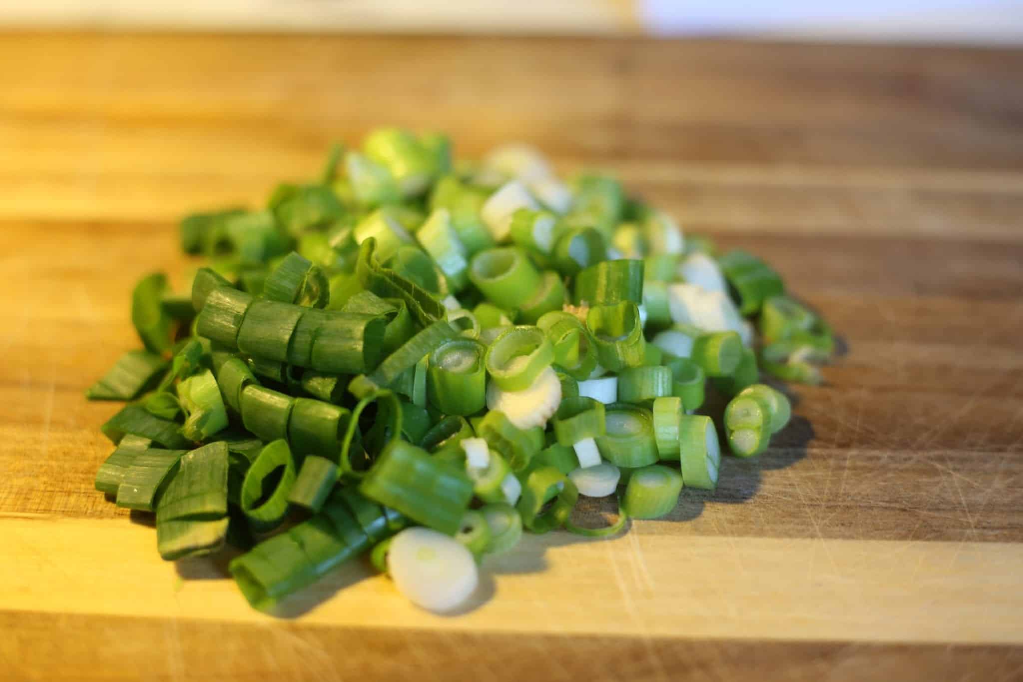 Fein geschnittene grüne Frühlingszwiebeln auf einem Holzbrett