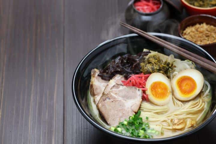 Tonkotsu-Ramen in schwarzer Schale mit Chashu, Kikurage, eingelegtem rotem Ingwer, Takana und halbiertem Ajitsuke Tamago