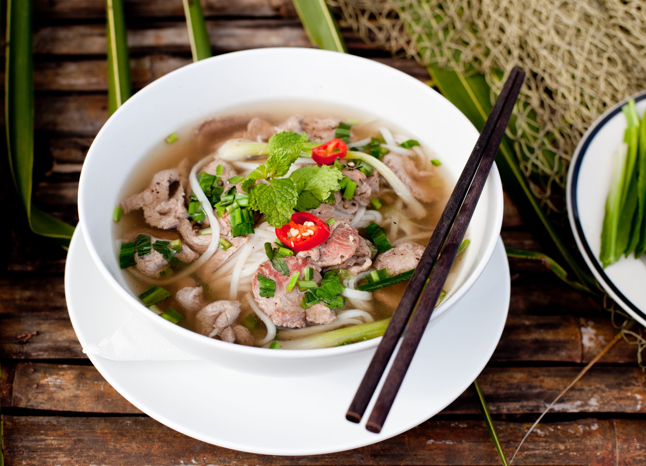 Vietnamesische Pho mit klarer Brühe, Reisnudeln und frischen Kräutern
